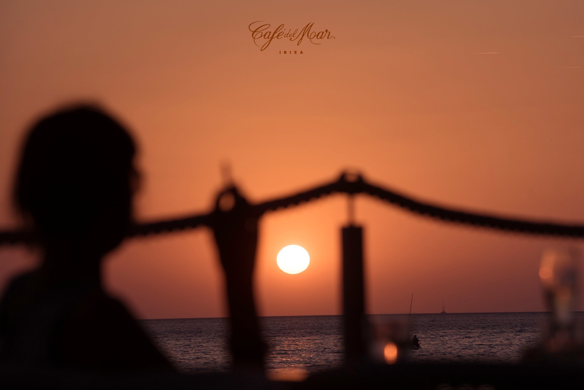 Zonsondergang bij Café del Mar Ibiza met silhouet en logo