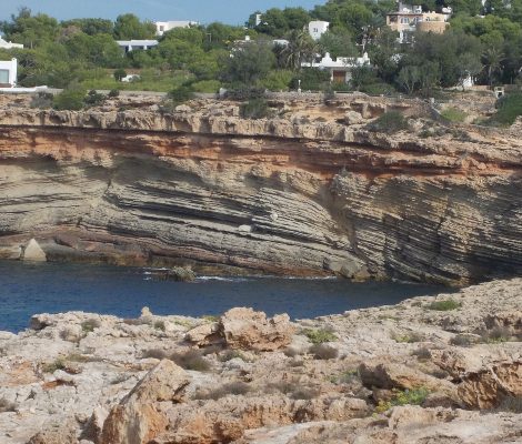 De rotsige westkust bij Cala Codolar op Ibiza — geologische lagen en kristalhelder water