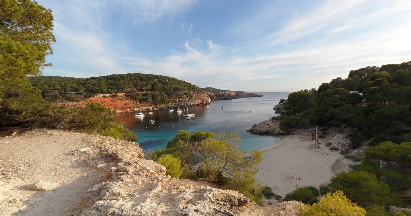 Panorama van Cala Saladeta op Ibiza — turquoise water, rotsen en het kleine zandstrand naast Cala Salada