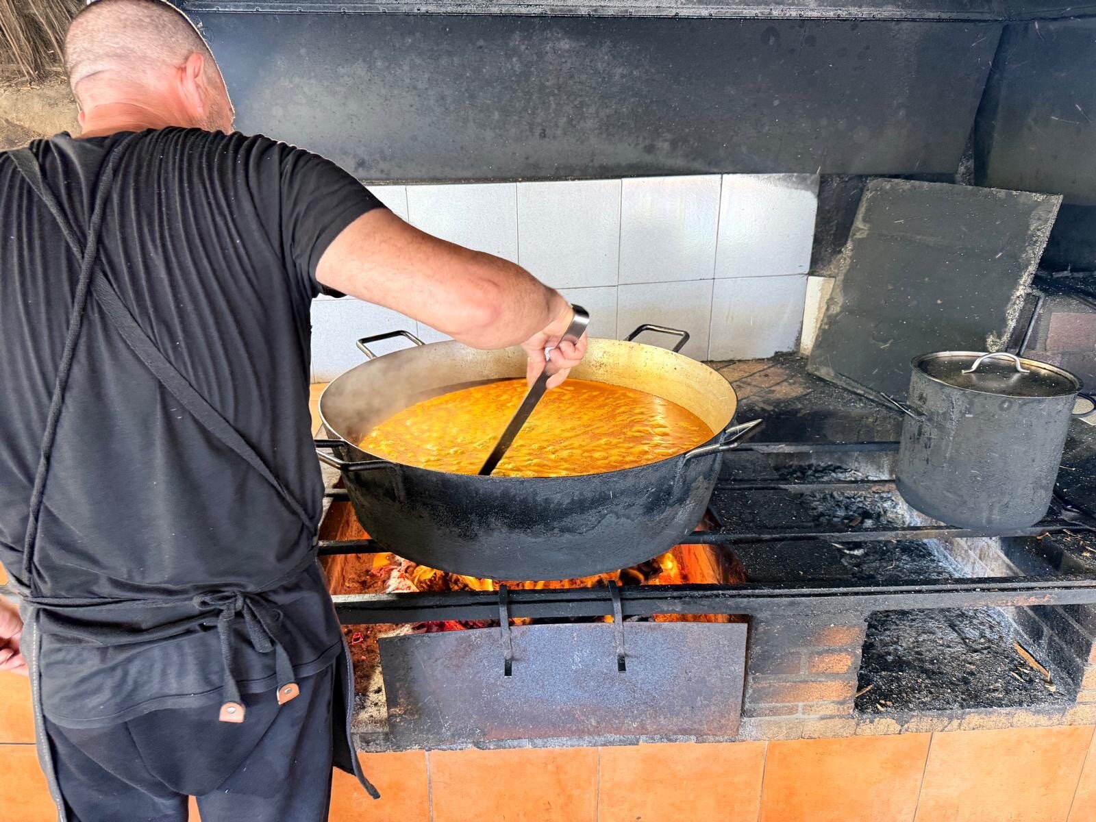 De chef van El Bigotes roert arroz a banda in een grote pan boven het houtvuur
