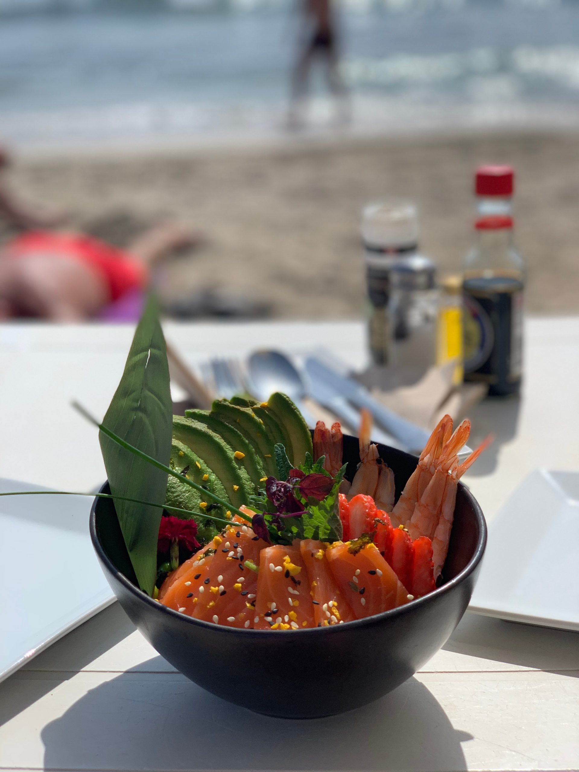 Poké bowl van Jockey Club met strand op de achtergrond