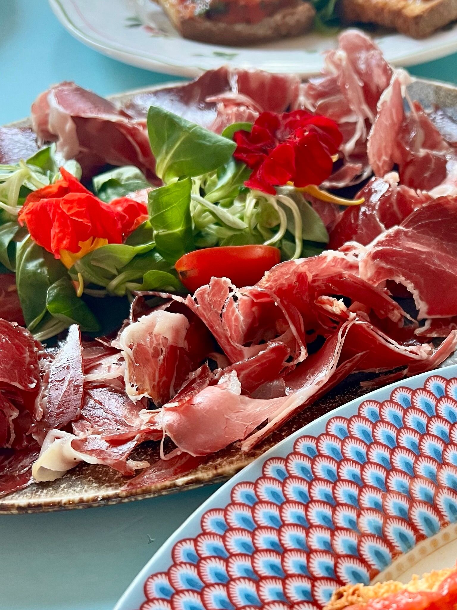 Proscuitto met salade en eetbare bloemen bij La Paloma