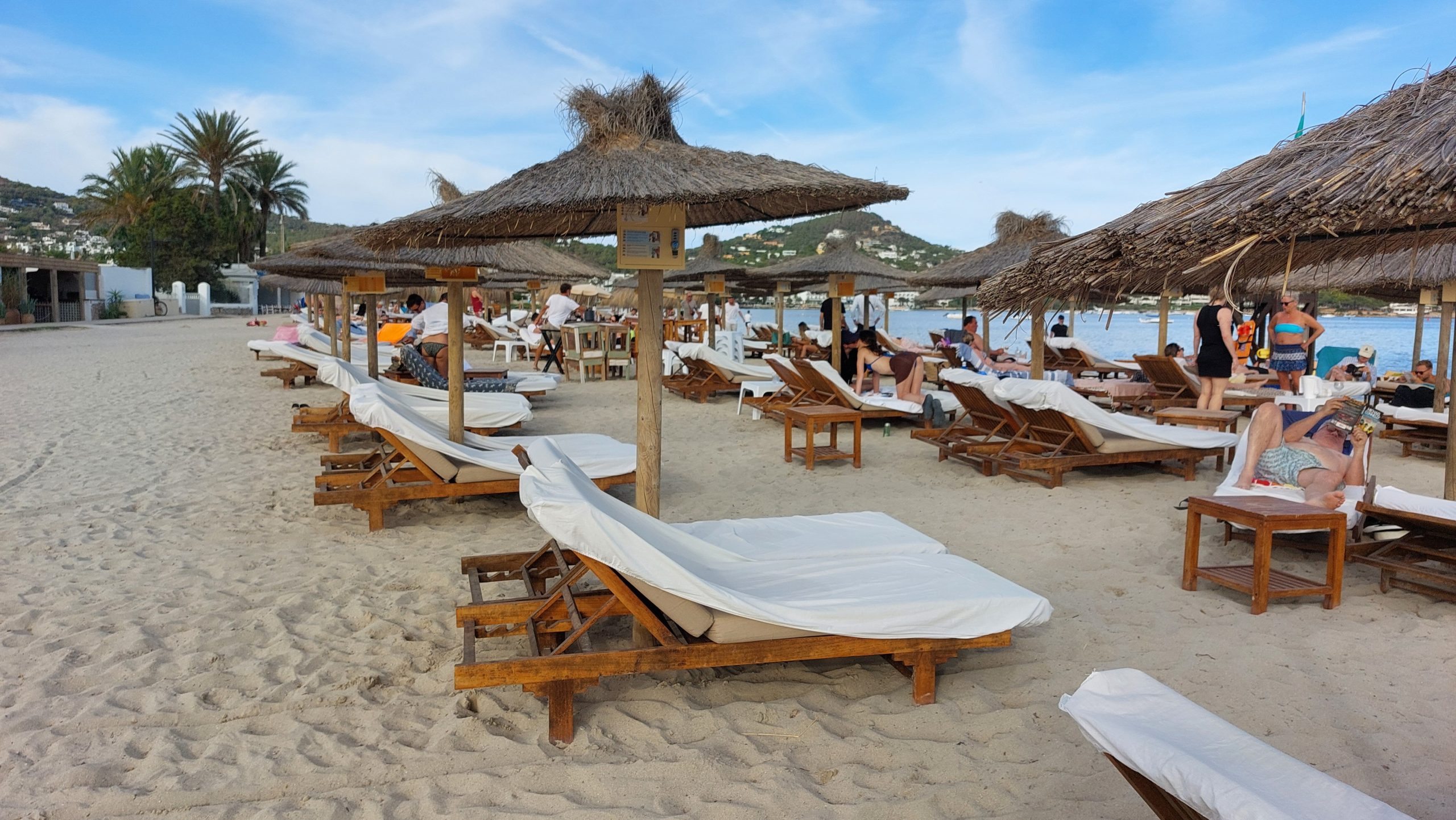 Houten ligbedjes en rieten parasols op Talamanca-strand