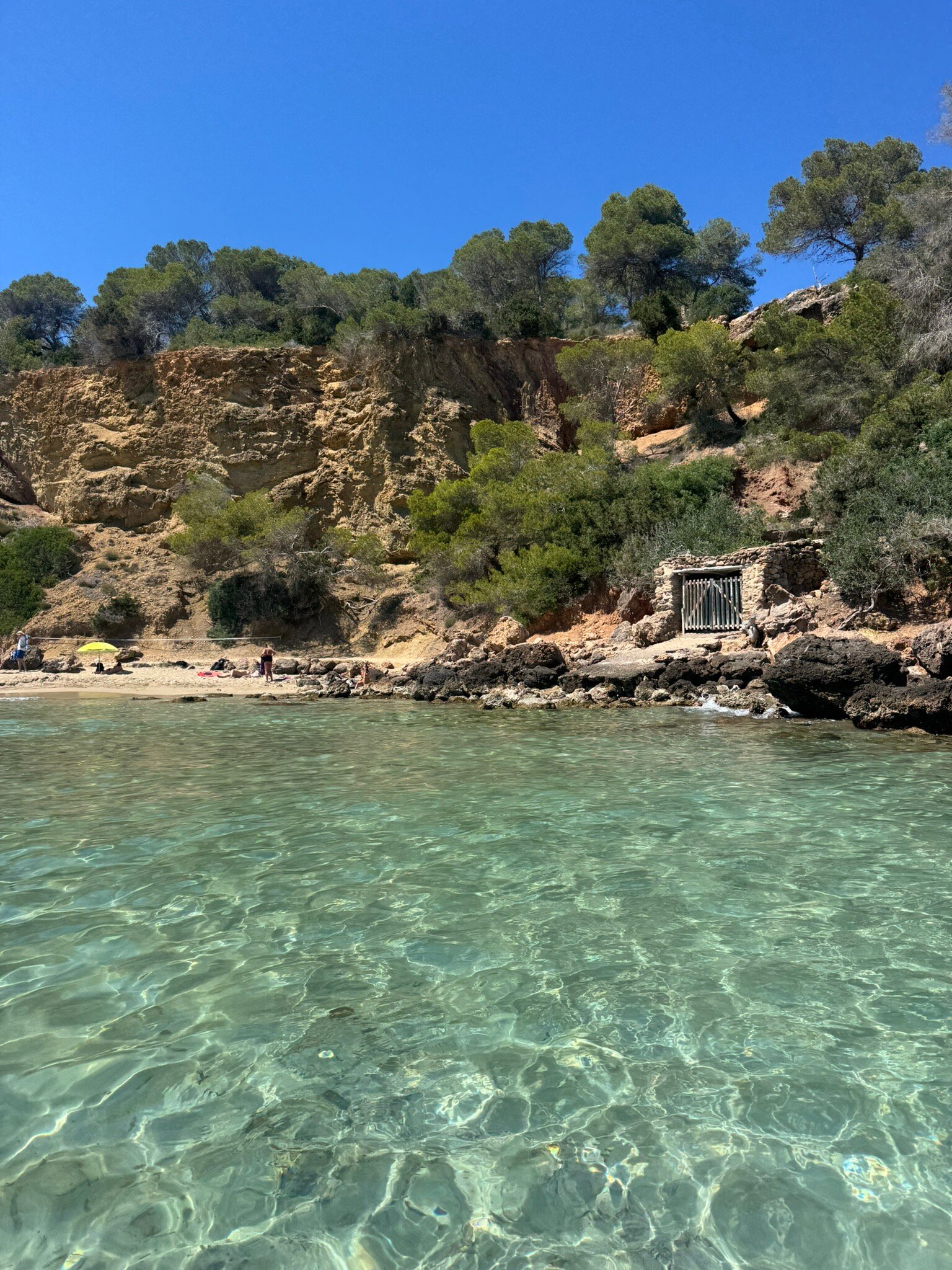 Cala Llenya Ibiza: familiestrand met rode kliffen bij Sant Carles 2 Kristalhelder water bij Cala Llenya met rode kliffen op de achtergrond