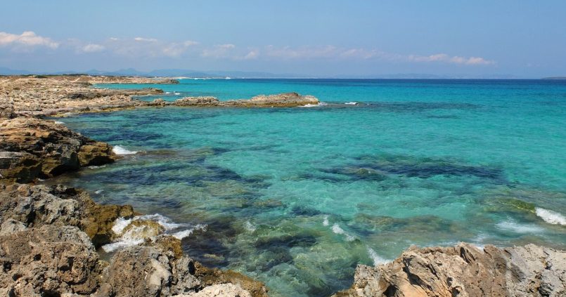 Platja de Sa Roqueta op Formentera, turquoise helder water over platte rotsen