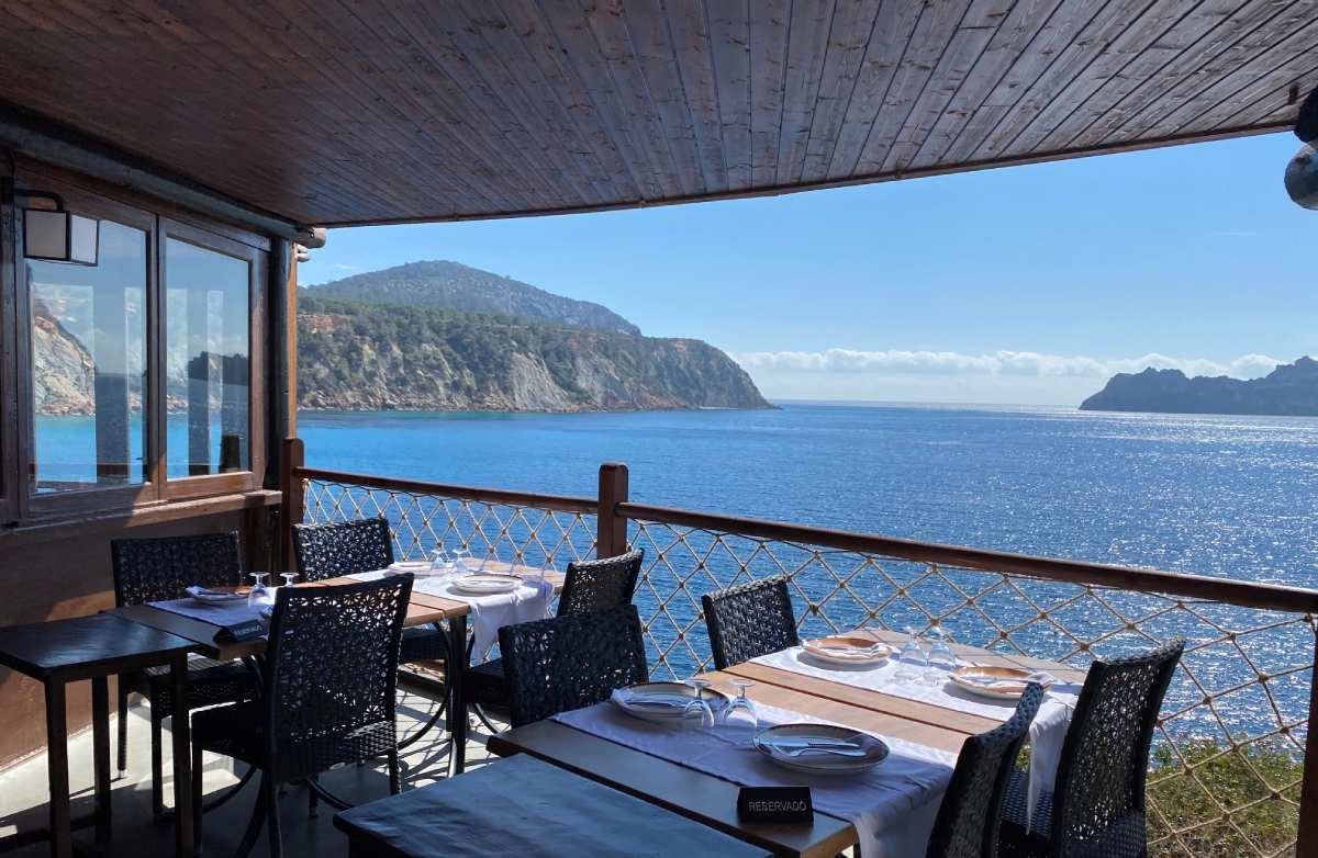 Het terras van restaurant Es Boldado boven Cala d'Hort op Ibiza, met gedekte tafels en uitzicht over de zee
