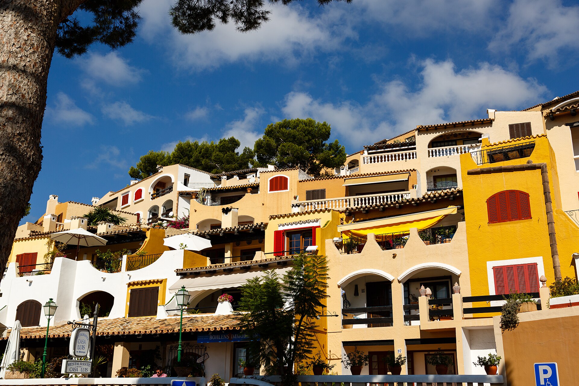 De okerkleurige, terrasvormige mediterrane gebouwen van Cala Fornells met tegeldaken en bogen, Mallorca