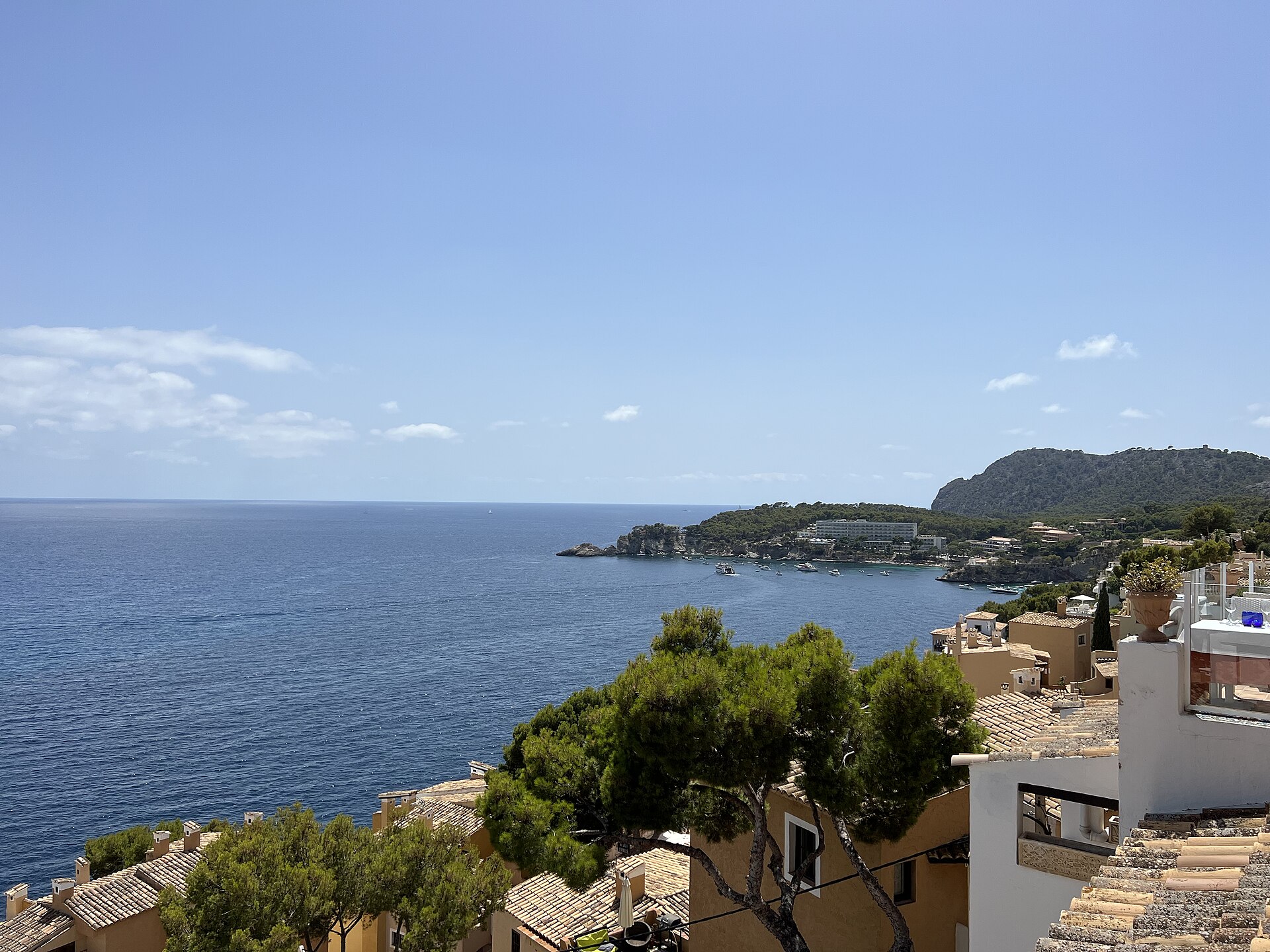 Uitzicht over de terracotta daken van Cala Fornells naar de diepblauwe zee en een kaap in de verte, Mallorca