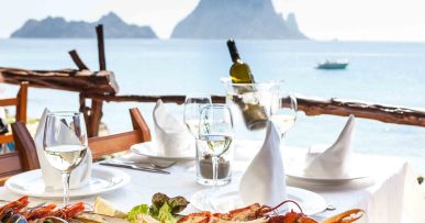 El Carmen Ibiza: strandrestaurant en paella aan Cala d'Hort 7 Zeevruchtenschotel op het terras van El Carmen met Es Vedrà op de achtergrond, Cala d'Hort, Ibiza