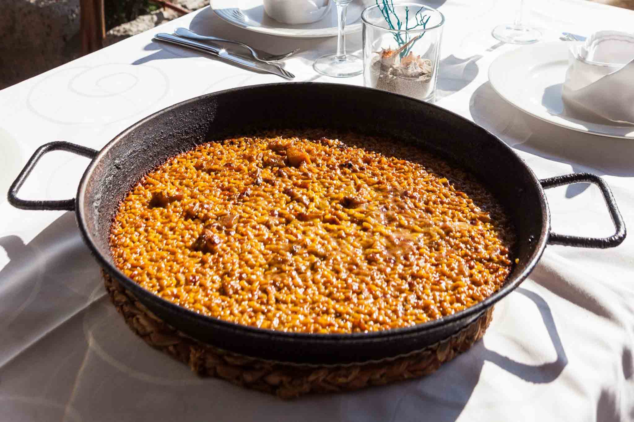 Een pan met traditionele paella op het terras van El Carmen aan Cala d'Hort, Ibiza