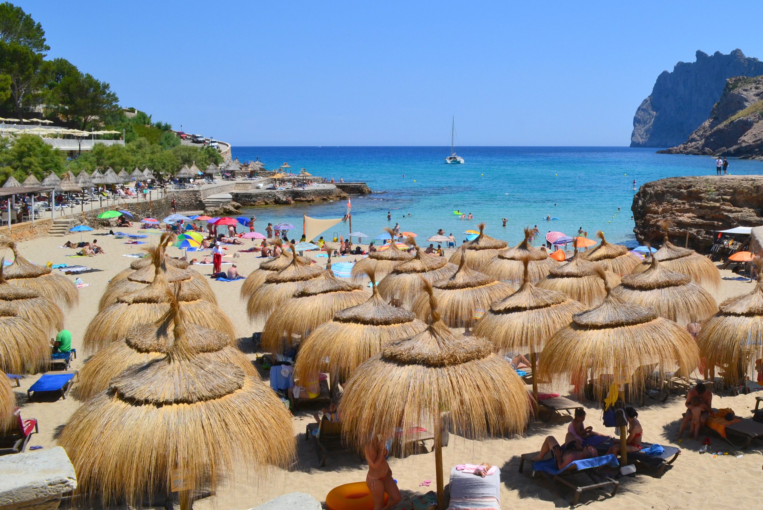 Het strandje Cala Barques bij Cala Sant Vicenç met rieten parasols, gouden zand en turquoise water, Mallorca