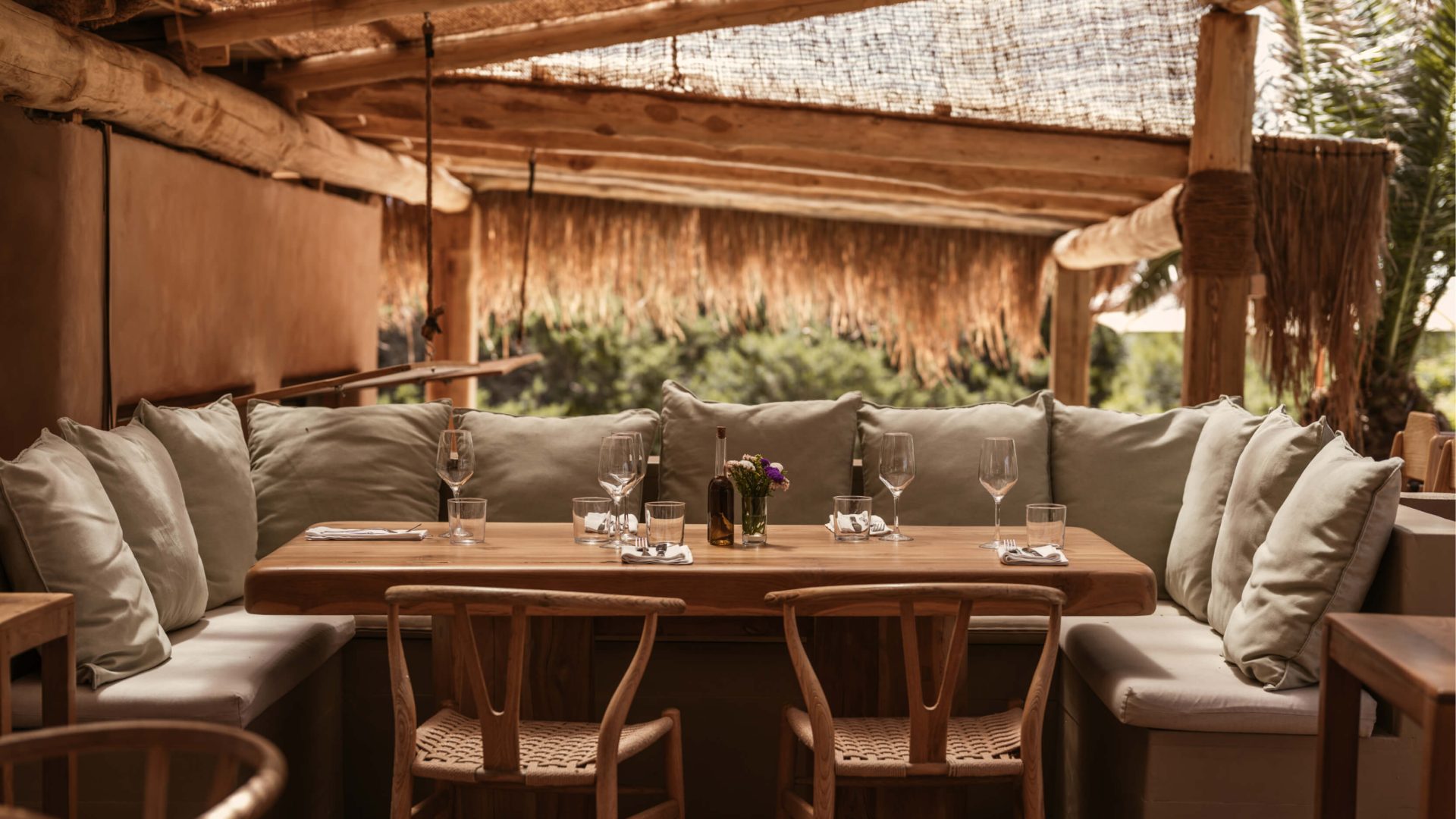 Een gedekte tafel onder de rieten pergola van strandrestaurant El Chiringuito in de duinen van Es Cavallet, Ibiza