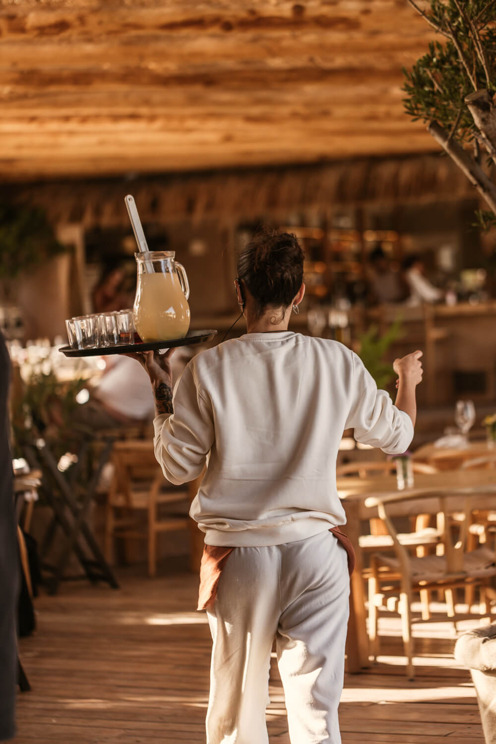Bediening met een dienblad in het warme licht van strandrestaurant El Chiringuito op Es Cavallet, Ibiza