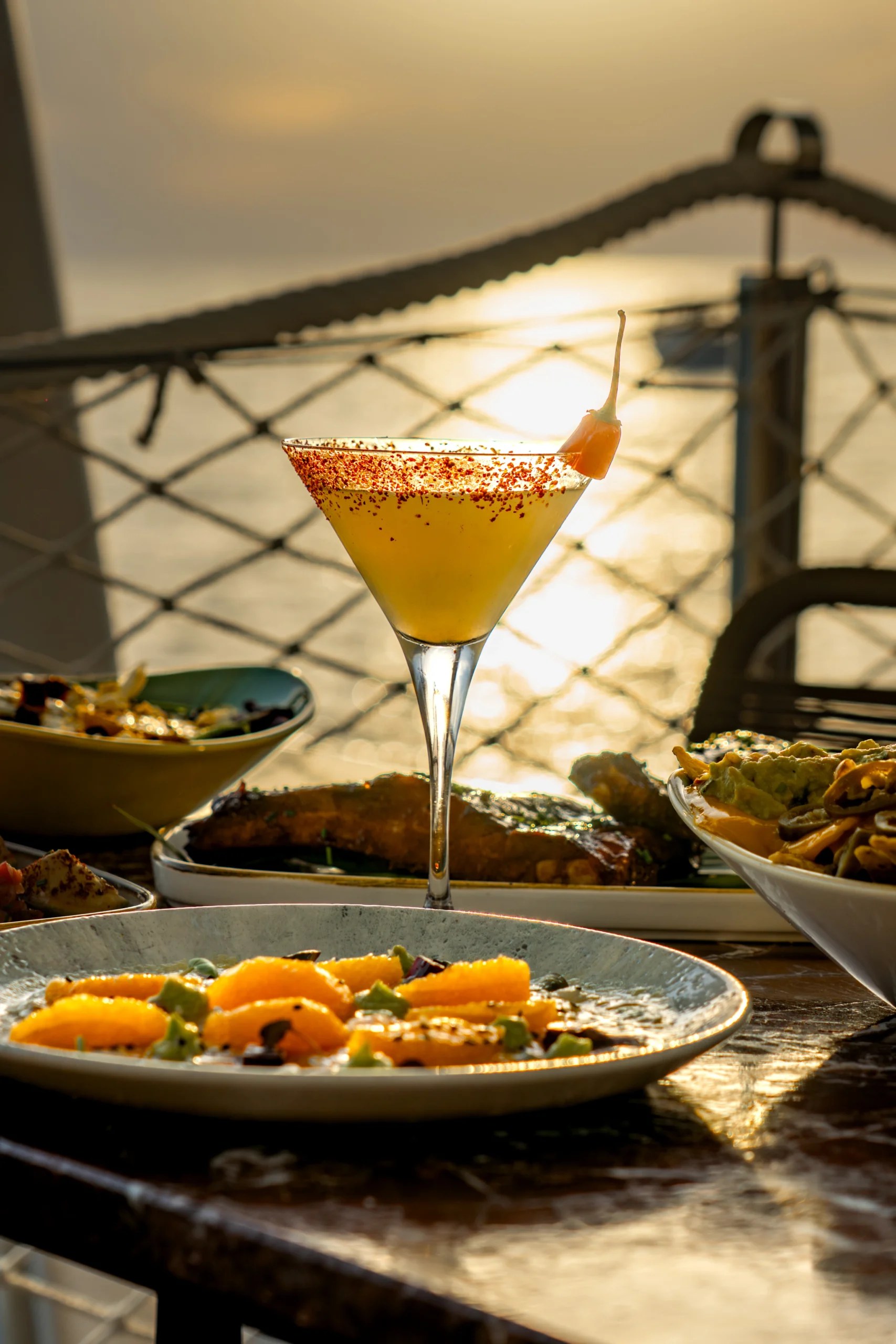 Cocktail met uitzicht op de zonsondergang over zee vanaf het terras van Savannah op de Sunset Strip in San Antonio, Ibiza