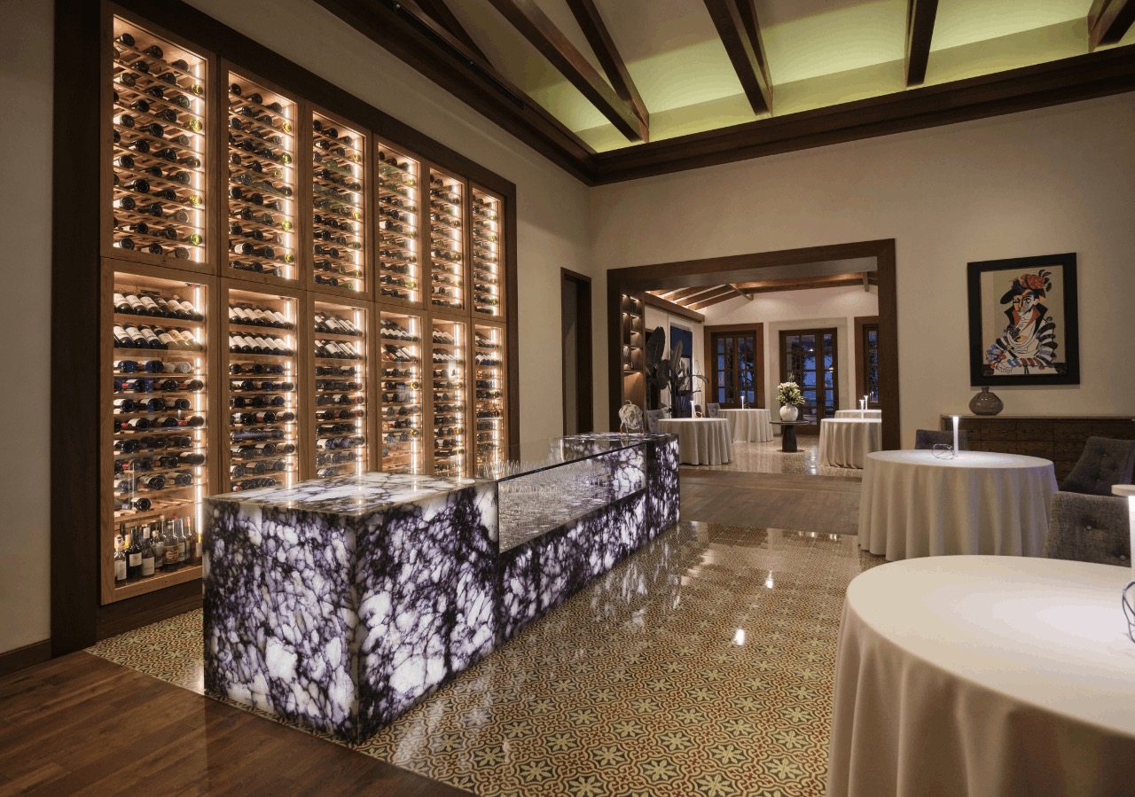 De elegante eetzaal van tweesterrenrestaurant Voro met een verlichte wijnmuur en een verlicht marmeren buffet, Canyamel, Mallorca