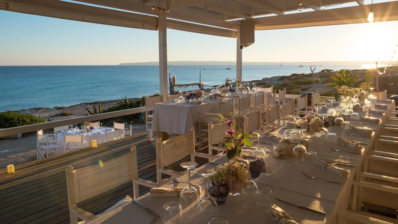 10.7 Formentera: zonsondergang en fusionkeuken aan Platja de Migjorn 2 Het overdekte terras van 10.7 met gedekte tafels en uitzicht op de zee