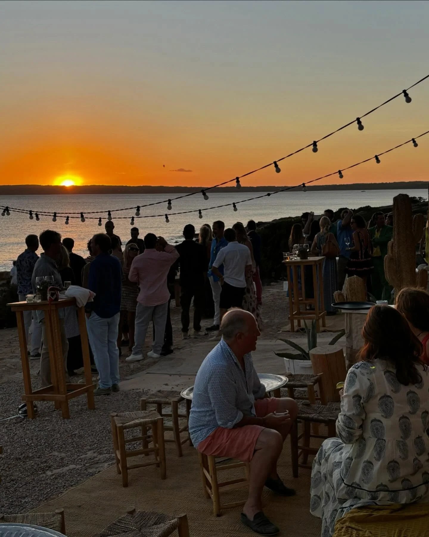 10.7 Formentera: zonsondergang en fusionkeuken aan Platja de Migjorn 3 Gasten kijken naar de zonsondergang boven de zee vanaf het terras van 10.7