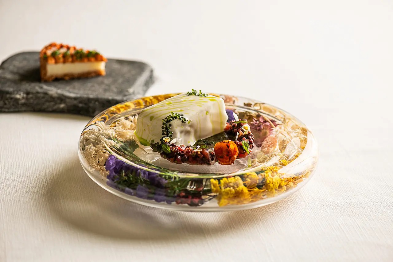 Een kunstig gepresenteerd gerecht van Andreu Genestra op een glazen bord met geperste gedroogde bloemen, Mallorca