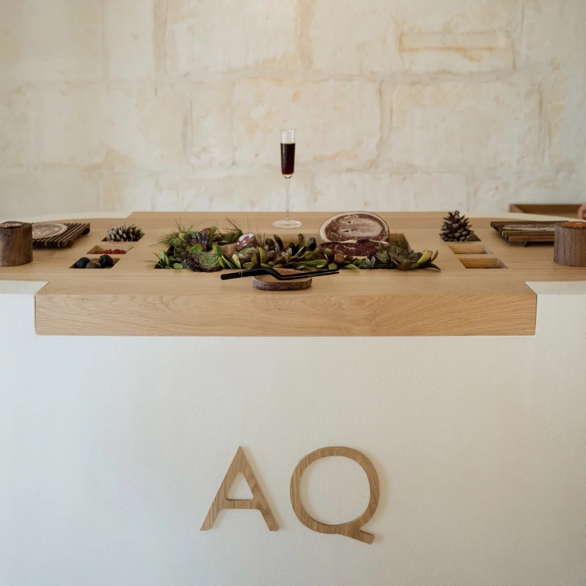 Houten tafel met kleine gerechten en het AQ-logo bij Aquiara