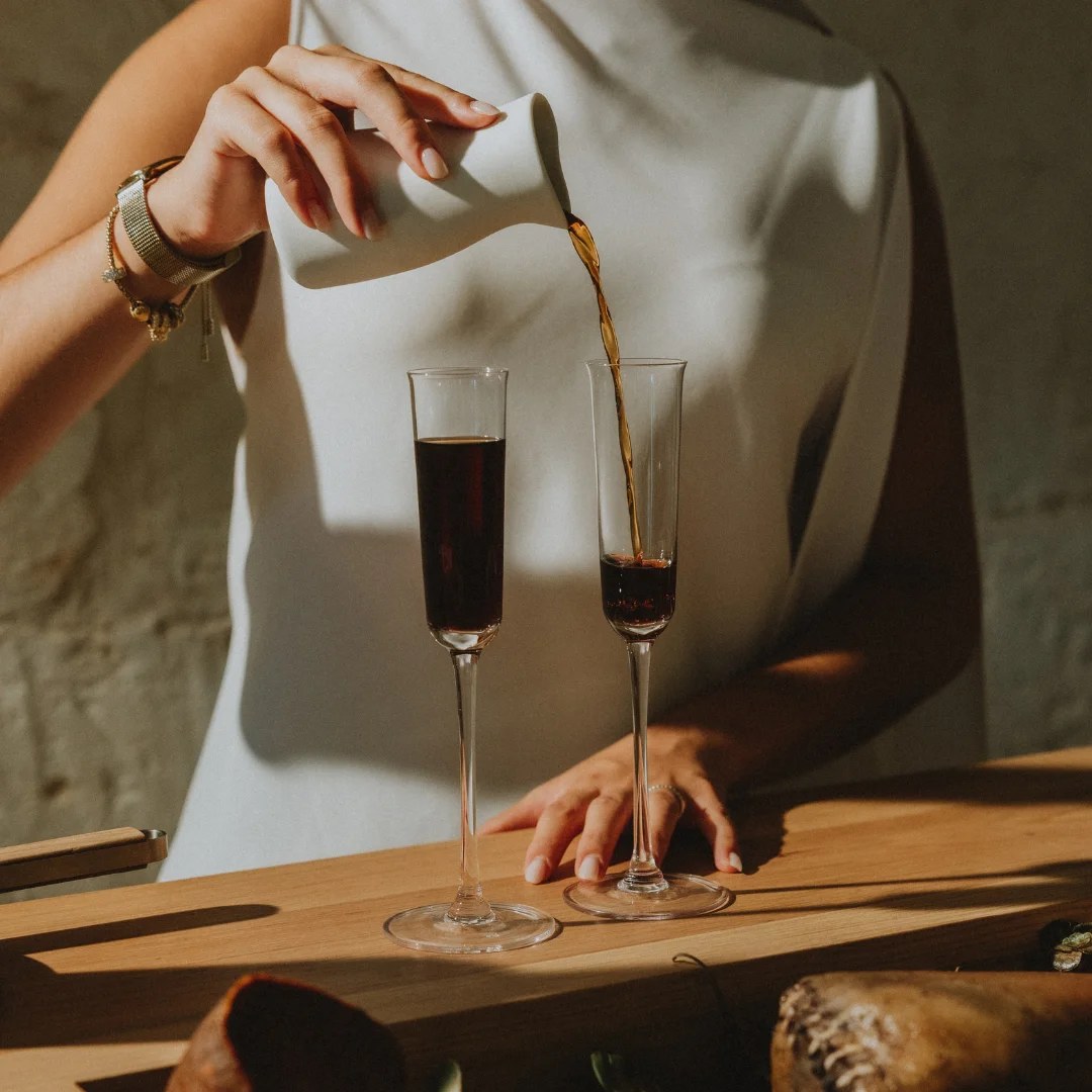 Er wordt een donkere drank in een glas geschonken bij Aquiara