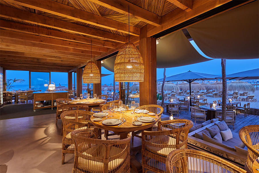Assaona Portixol (Palma): gastrobeachclub op het zand, het hele jaar open 5 Avonddiner op het terras van Assaona met warm licht en zicht op de haven van Portixol