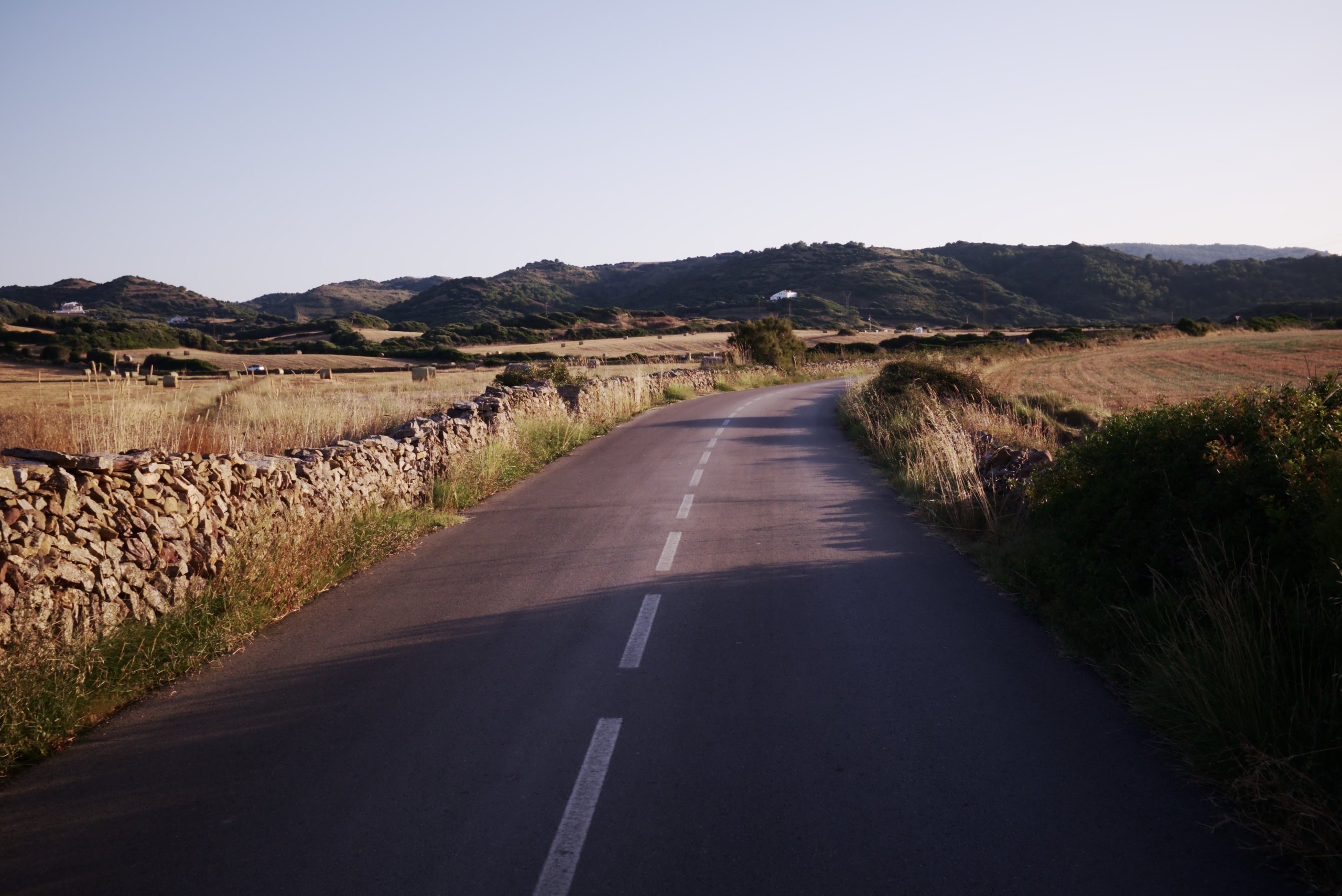 Landweg tussen droge stenen muren op Menorca in het avondlicht