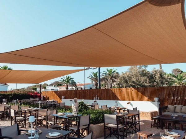 De Zen Garden van Bambú Menorca met tafels en stoelen onder zonnezeilen