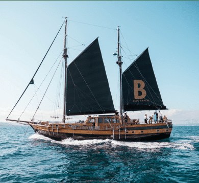 De zeilboot van Beso Beach met zwarte zeilen en de letter B op het zeil, op zee bij Formentera