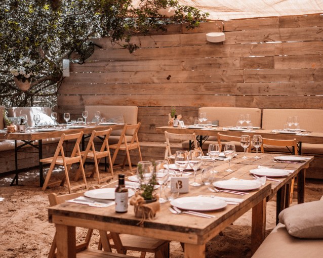 Gedekte houten tafels op het terras van Beso Beach Formentera