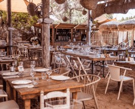 Het overdekte rustieke eetgedeelte van Beso Beach met houten tafels en stoelen