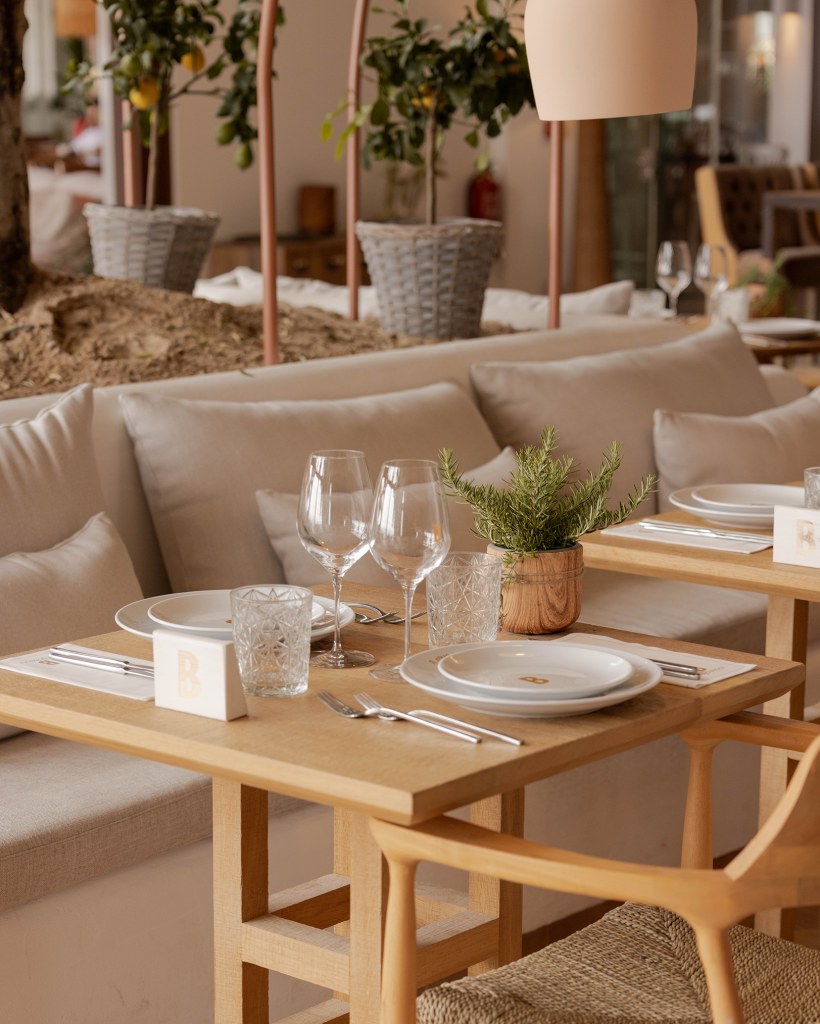 Beso Beach Palmanova (Mallorca): barefoot-luxury aan het strand 6 Gedekte tafel met glaswerk en een plant in het restaurant van Beso Beach Mallorca