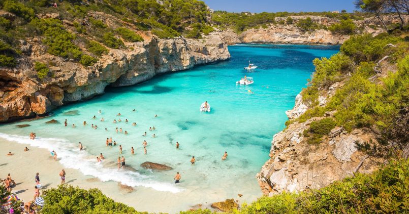 Turquoise water en een vol strandje in de baai Caló des Moro op Mallorca in augustus