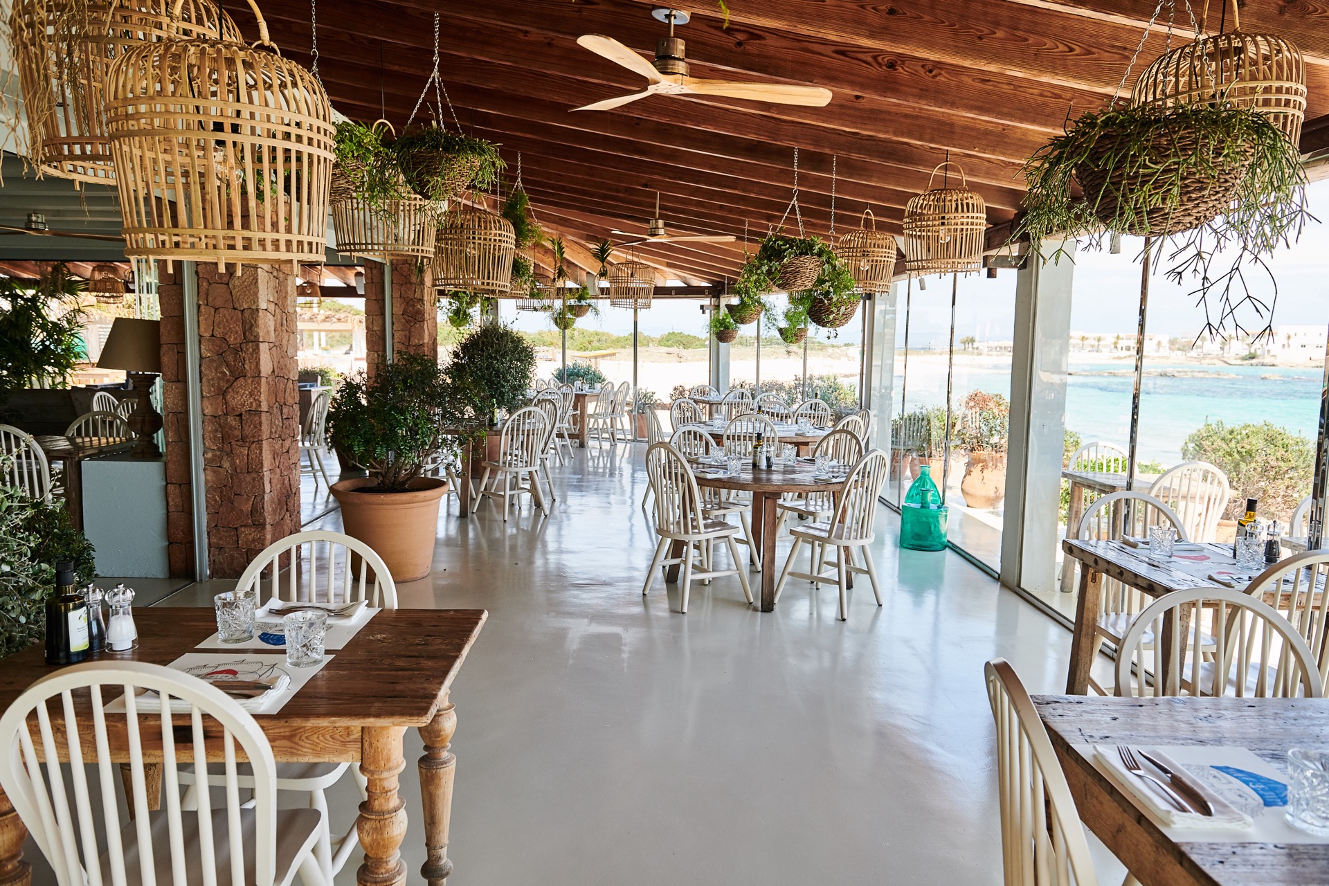 De eetzaal van Bocasalina met houten dak, rieten lampen en uitzicht op zee