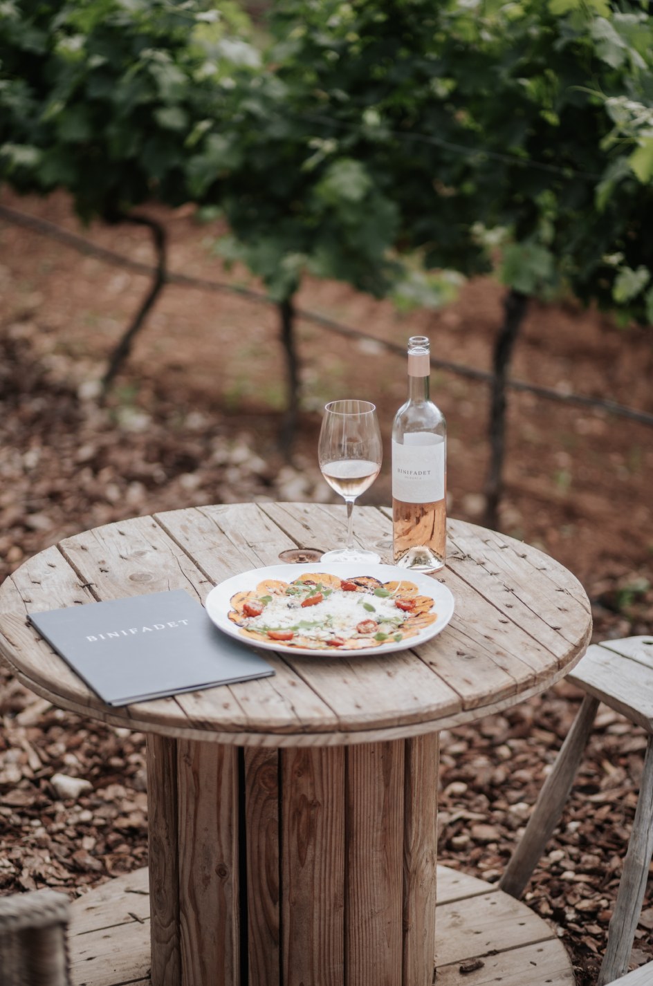 Bodegas Binifadet Menorca: lunch en wijnproeven tussen de wijnstokken 4 Rustieke tafel met een fles rosé en een hapje tussen de wijnstokken van Bodegas Binifadet