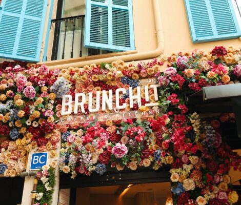 De met bloemen bedekte gevel van BrunchIT in Palma met de blauwe luiken