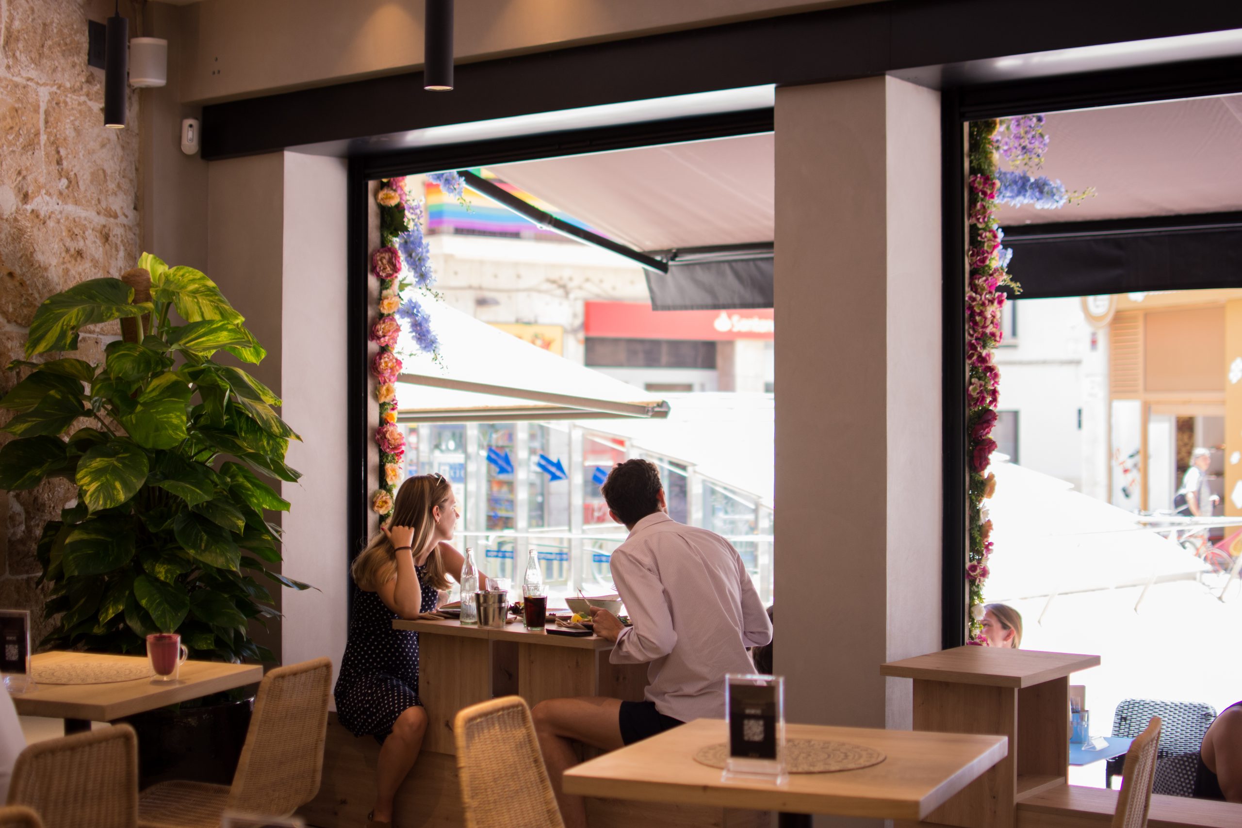 Tafel aan het met bloemen omlijste raam van BrunchIT in Palma