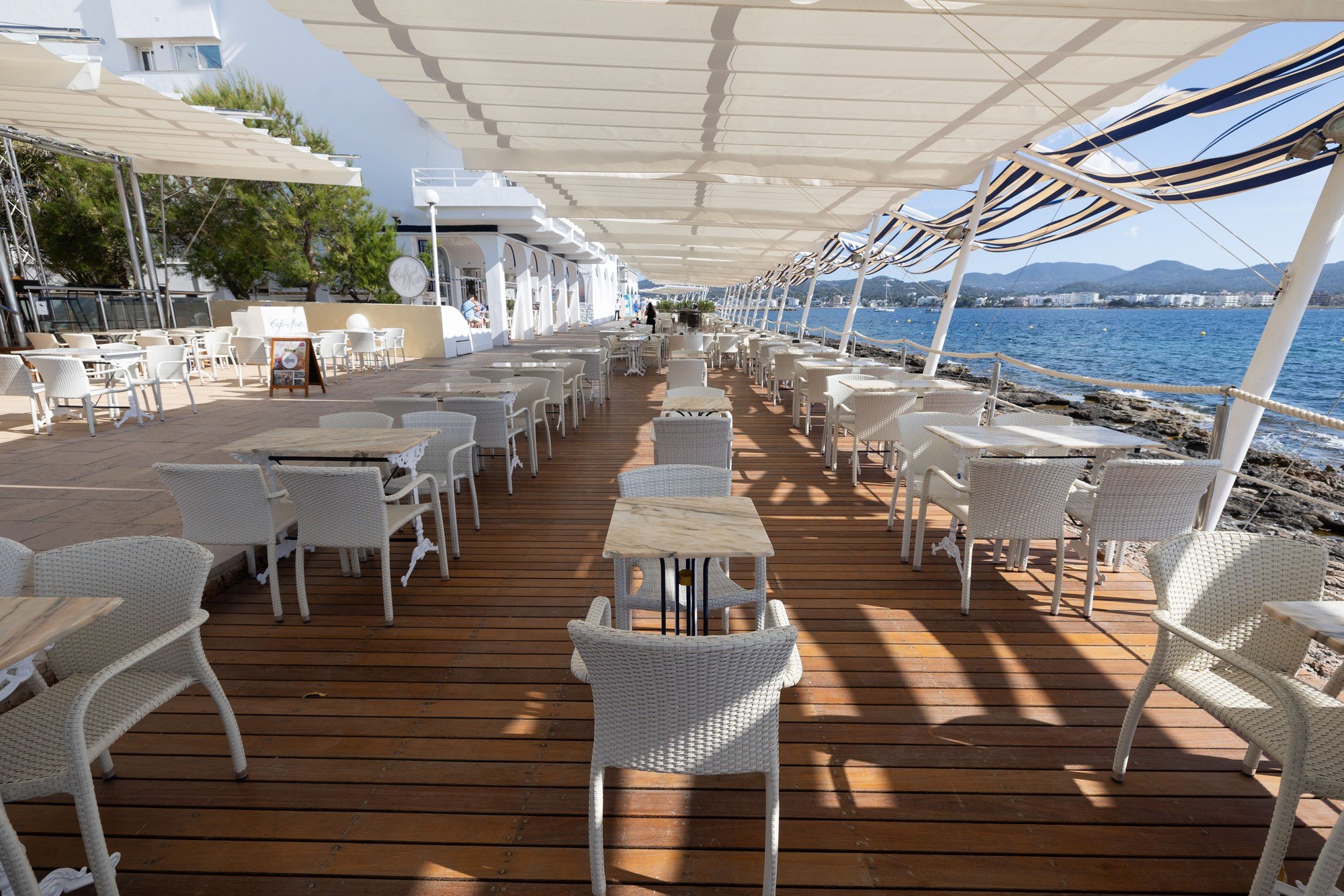 Het houten terras van Café del Mar aan de rotskust van Sant Antoni, overdag zonder publiek