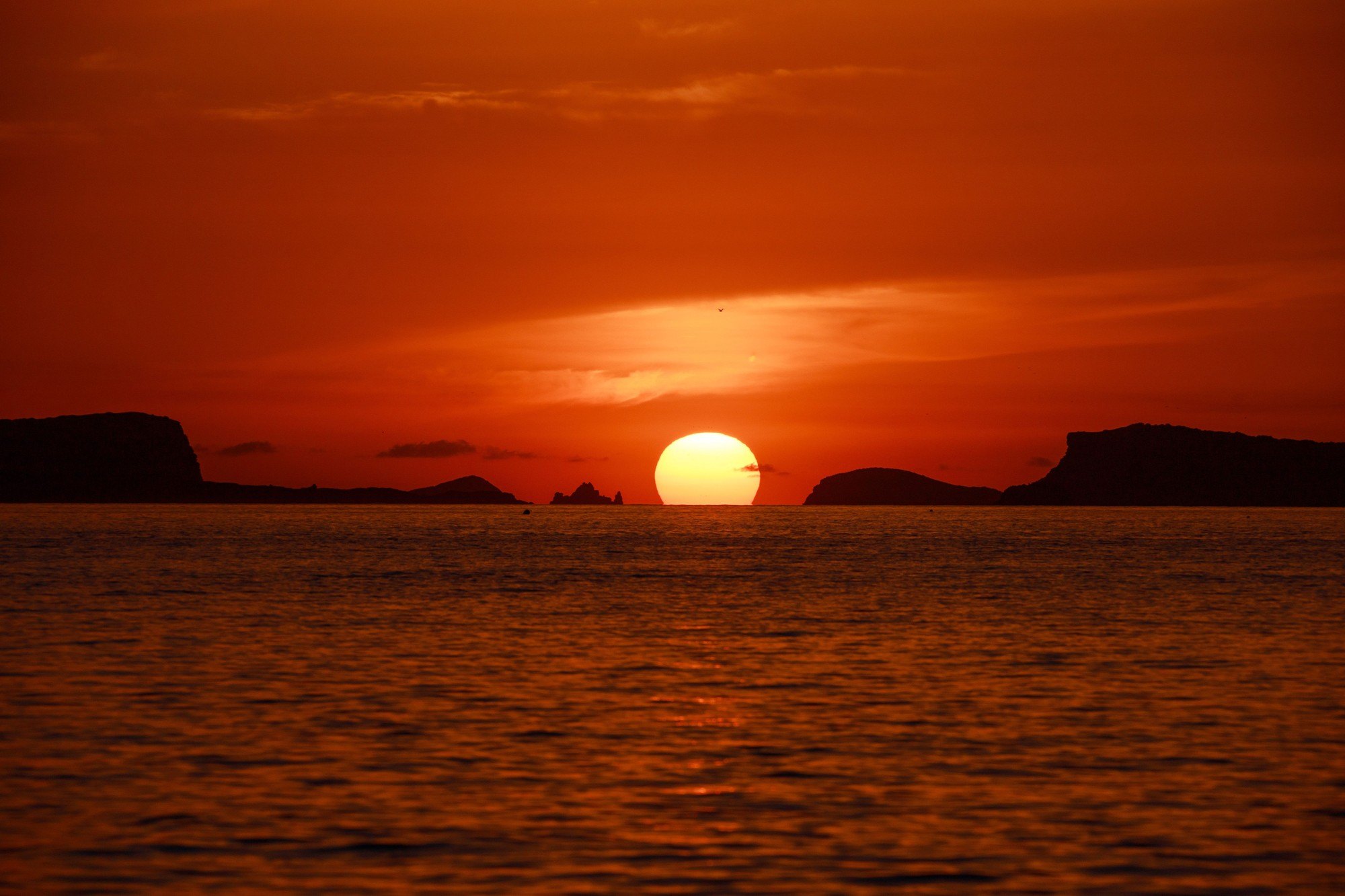 De zon zakt tussen de eilandjes voor de kust van Sant Antoni in zee, gezien vanaf Café del Mar