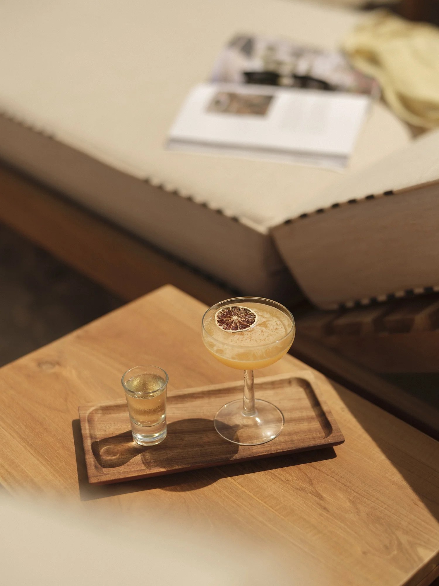 Cocktail op een houten dienblad bij een ligbed van Cala Bonita