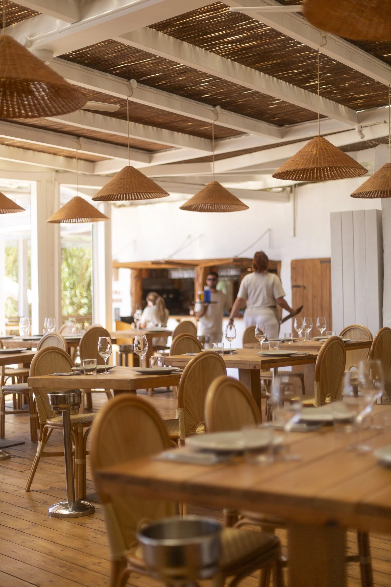 De lichte eetzaal van Cala Bonita met rieten lampen en houten tafels