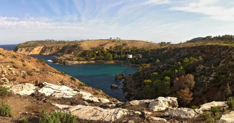 De baai van Es Canaret op de noordkust van Ibiza, met turquoise water, de witte villa met toren en daarachter de punta de Xarracó