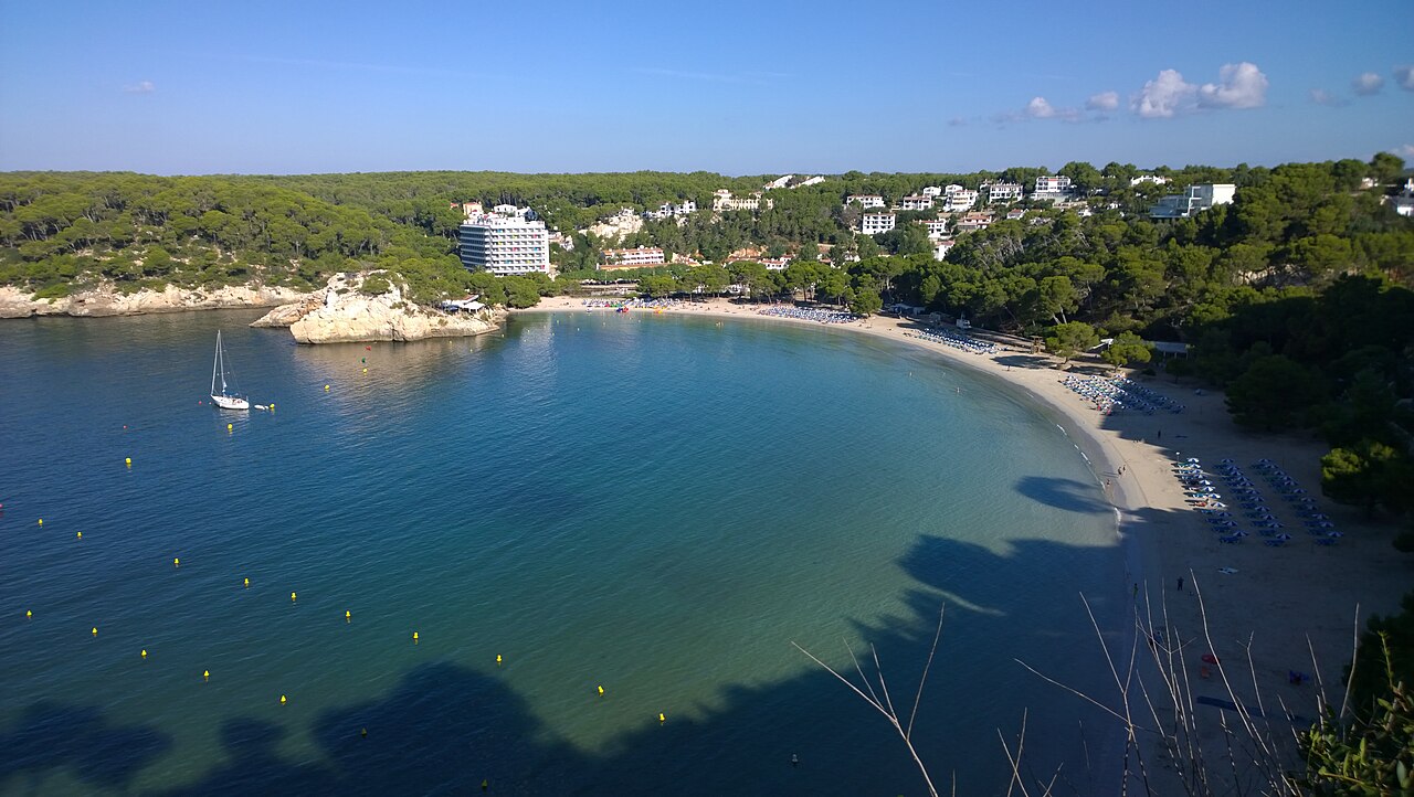Cala Galdana Menorca: de baai, parkeren en lopen naar Macarella 1 De hoefijzervormige baai van Cala Galdana op Menorca met het dorp en de hotels erboven