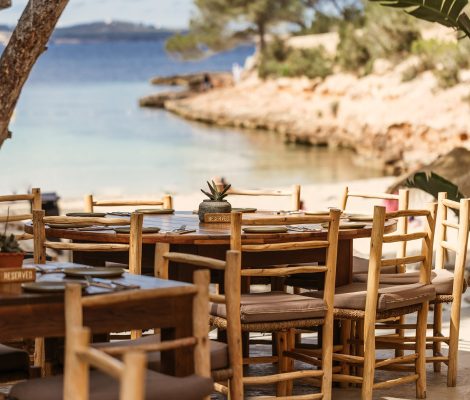 Het terras van het strandrestaurant van Cala Gracioneta met houten tafels en uitzicht op de kleine baai