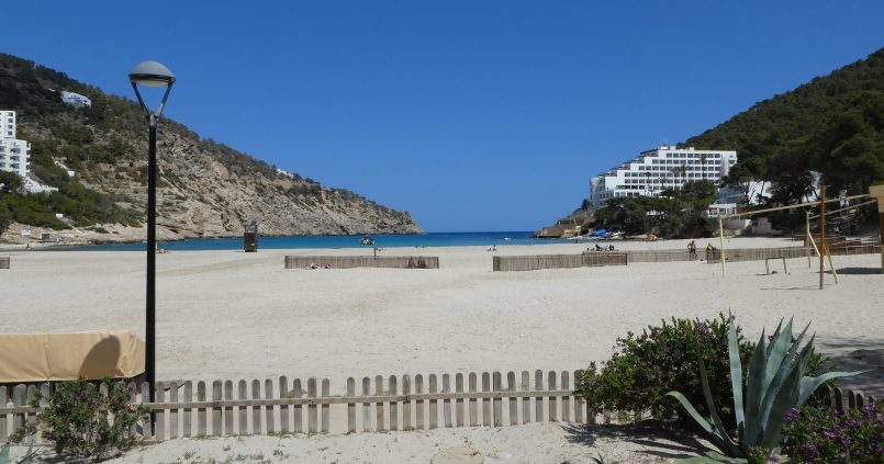 Het brede zandstrand van Cala Llonga met de smalle baai tussen twee beboste heuvels aan de oostkust van Ibiza