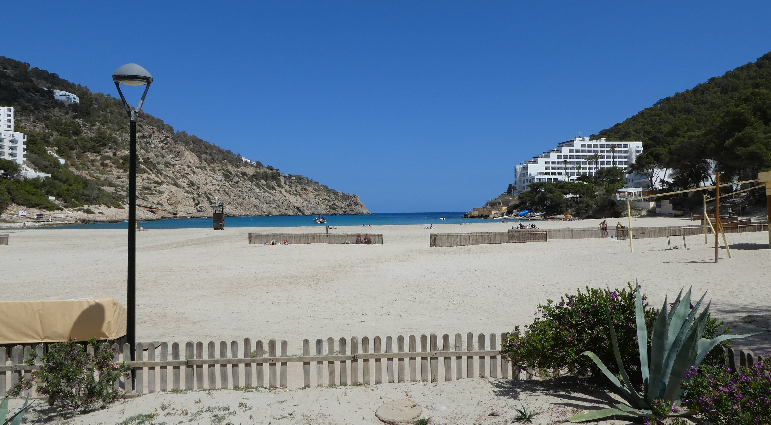 Het brede zandstrand van Cala Llonga met de smalle baai tussen twee beboste heuvels aan de oostkust van Ibiza