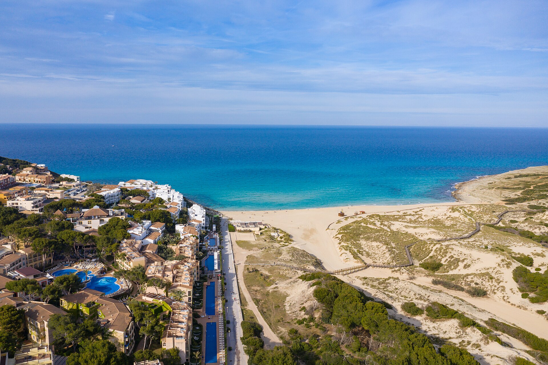 Luchtfoto van het strand en de duinen van Cala Mesquida met de hotels van het dorp aan de rand
