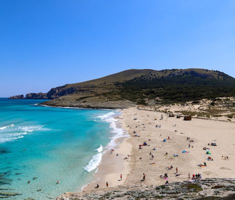 Het zandstrand van Cala Mesquida in het noordoosten van Mallorca met turquoise water en een beboste heuvel erachter