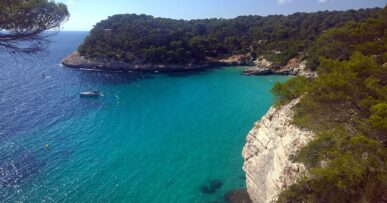 Het heldere turquoise water van Cala Mitjana op Menorca met witte kalksteenkliffen