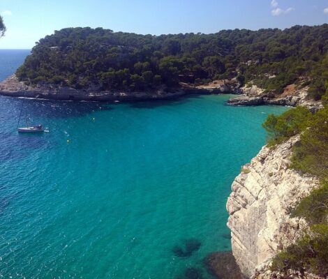 Het heldere turquoise water van Cala Mitjana op Menorca met witte kalksteenkliffen