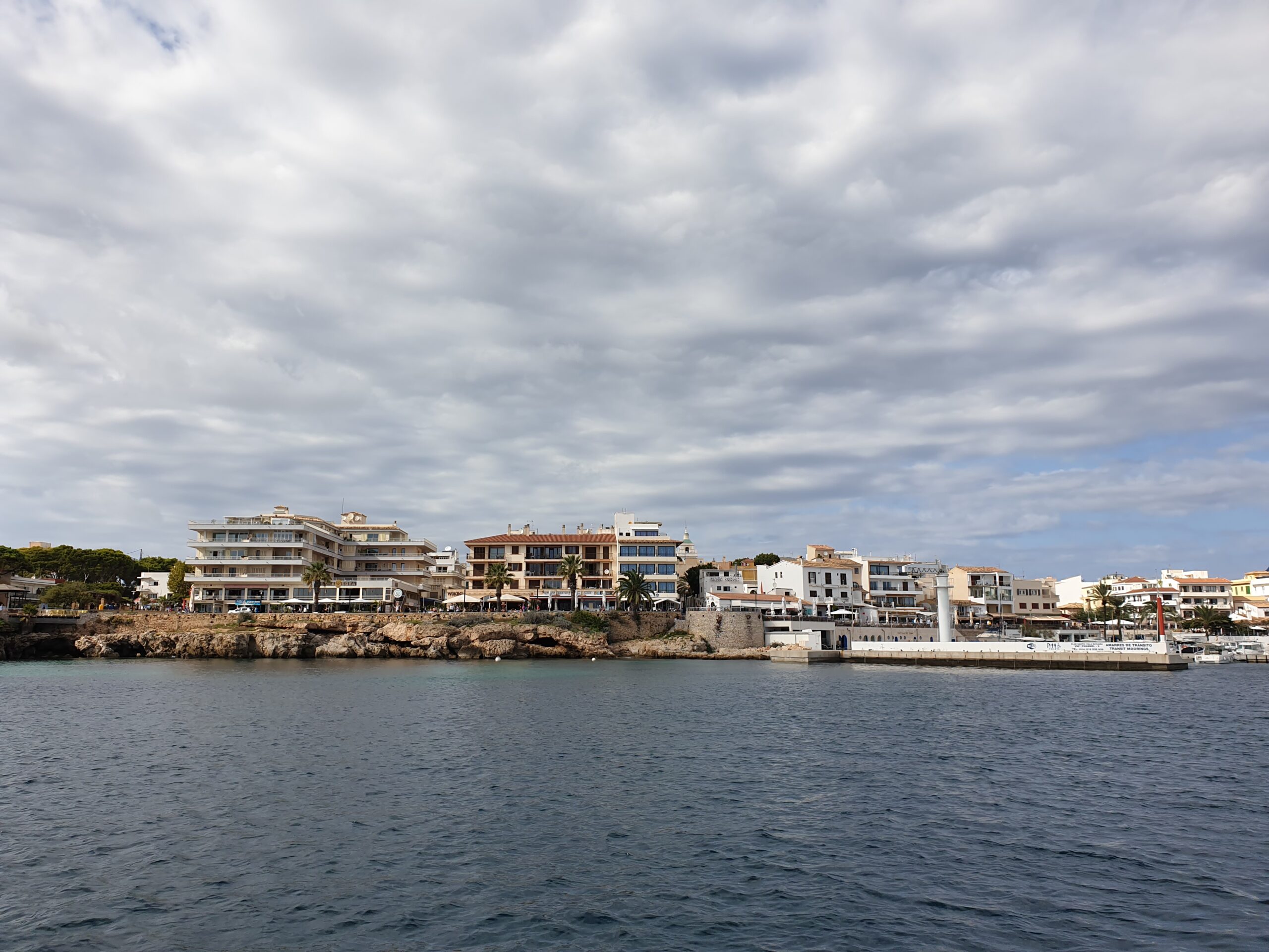 De vissershaven van Cala Ratjada met de gebouwen langs de Passeig Colom, gezien vanaf de havenmuur